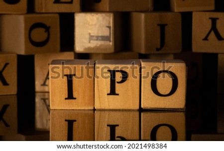 IPO or initial public offer by letters on wooden beads or block on the rupees with reflection and more blocks behind with dark background.