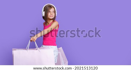 Portrait Of Joyful Teen Girl Wearing Headphones and Shopping Bags Over Purple Background, Copy Space. 