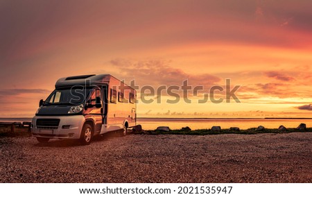 Camper van at sunset on beach Royalty-Free Stock Photo #2021535947