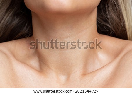 A close-up view of a young woman's neck and collarbone . Lines on the neck. Wrinkles, age-related changes, rings of Venus, goosebumps. Skin care
