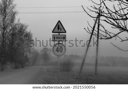 Foggy morning by an empty countryside road with traffic signs in black and white
