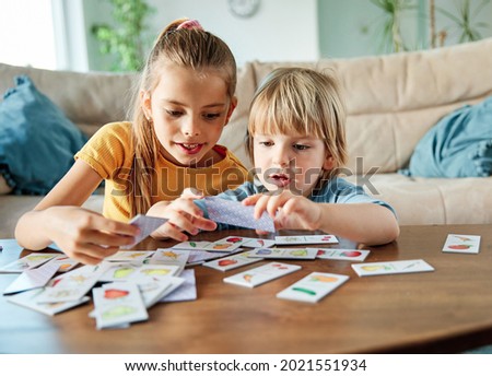 Portret of brother and sister having fun together playing board game at home Royalty-Free Stock Photo #2021551934