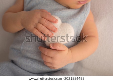 Child's hand, fingers close up. Newborn baby hands, happy childhood concept, healthcare, IVF, hygiene. Newborn holding a soft heart in his hands. Black and white photo.