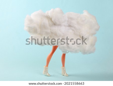 Doll legs behind the clouds on a blue background. Minimalism