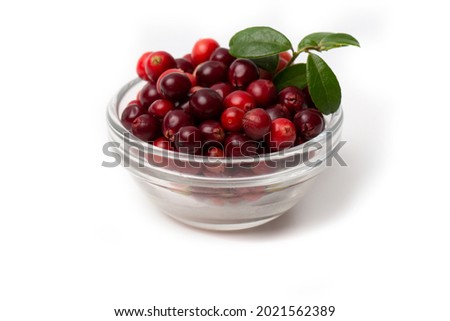 Red cranberry berry with green leaves in a transparent bowl isolated on a white background. Royalty-Free Stock Photo #2021562389