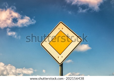 priority road sign with blue sky and clouds