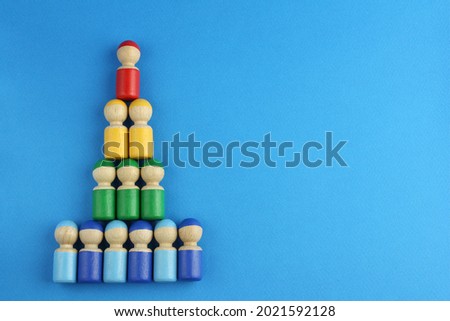 pyramid of multicolored wooden toy people on blue background with copy space, concept of social rating or class inequality and wealth rating or company business structure  Royalty-Free Stock Photo #2021592128