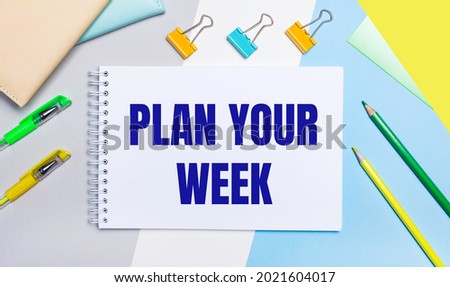 On a gray and blue background are stationery of yellow-green color, a notebook with the text PLAN YOUR WEEK. Flat lay.