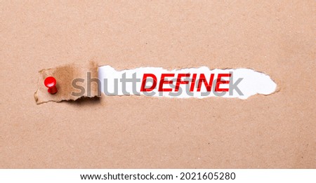 Beneath the torn strip of kraft paper attached with a red button is a white paper DEFINE