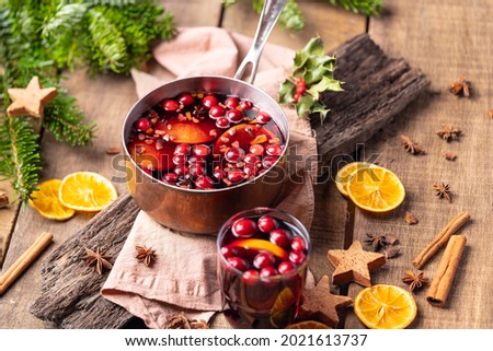  Hot mulled red wine drink with citrus, apples, cinnamon sticks, cloves and anise in cooking pan on wooden background