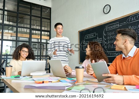 Four diverse multiracial young professional business startup gen z team students group working on project listen to Asian leader in contemporary office classroom with gadgets. Diversity concept. Royalty-Free Stock Photo #2021619692
