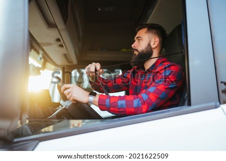 Truck driver fastens seatbelt  and preparing for the next destination. Royalty-Free Stock Photo #2021622509