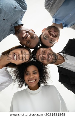 Close up vertical low angle portrait of smiling multiethnic diverse employees pose together look at camera laughing. Happy young multiracial workers friends have fun show unity. Diversity concept. Royalty-Free Stock Photo #2021631848