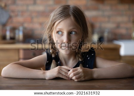 Head shot portrait of sly little girl with guilty scared face and shut mouth. Funny kid looking away, keeping silence about tricks, avoiding punishment. Childhood, young age problems concept