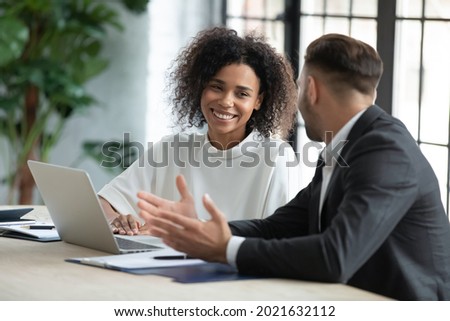 Smiling diverse employees colleagues have fun laugh cooperate brainstorm on computer at office team meeting. Happy multiethnic businesspeople work together on laptop discuss business ideas in group. Royalty-Free Stock Photo #2021632112