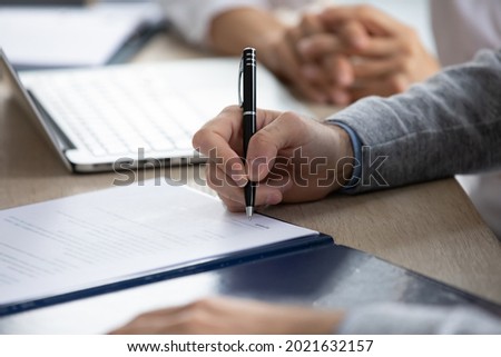 Crop close up of male employee worker put signature on document close deal at meeting in office. Man client or customer sign paperwork make agreement with business partner. Cooperation concept.