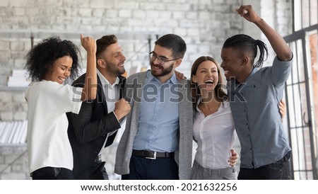 Overjoyed young multiethnic businesspeople have fun celebrate shared business success or victory in office. Smiling multiracial diverse employees feel excited win get good results. Teamwork concept. Royalty-Free Stock Photo #2021632256