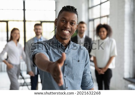 Portrait of smiling young African American man stretch hand for handshake get acquainted at workplace. Happy millennial mixed race male employee meet newcomer in office. Recruitment concept. Royalty-Free Stock Photo #2021632268