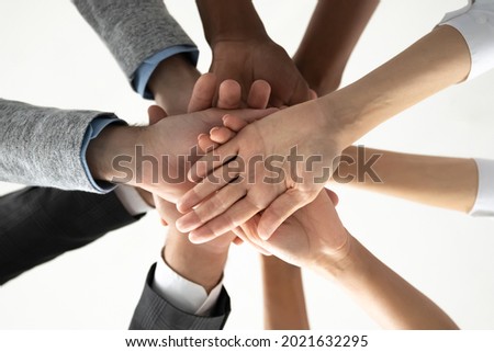 Crop close up of diverse international people join stack hands in pile motivated for shared team success or achievements. Multiethnic employees involved in teambuilding activity. Teamwork concept.