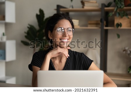 Close up dreamy smiling businesswoman in glasses distracted from laptop, looking to aside, pensive young woman visualizing good future, dreaming about new opportunities, pondering project strategy Royalty-Free Stock Photo #2021632391