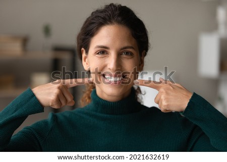 Head shot portrait happy woman pointing fingers at healthy toothy smile, straight white teeth, excited satisfied client recommending dental whitening service or toothpaste, oral hygiene concept Royalty-Free Stock Photo #2021632619