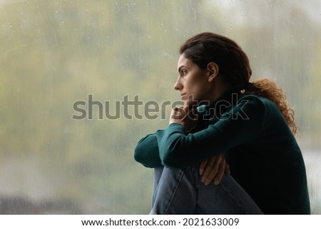 Side view frustrated thoughtful woman looking out rainy window in distance alone, lost in thoughts, upset unhappy young female feeling lonely and depressed, thinking about relationship problems Royalty-Free Stock Photo #2021633009