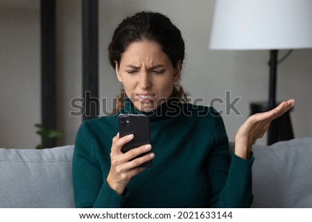Close up angry dissatisfied woman looking at phone screen, unhappy confused young female having problem with broken smartphone or internet fraud, slow internet connection, reading bad news in message Royalty-Free Stock Photo #2021633144