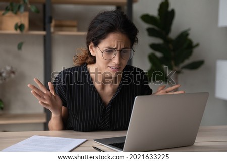 Close up upset businesswoman in glasses having problem with laptop, broken or discharged device, confused unhappy woman looking at computer screen, reading bad news, unexpected debt or spam Royalty-Free Stock Photo #2021633225
