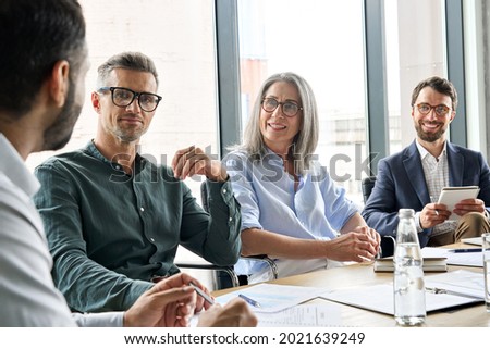 Executive team business people listening to ceo negotiating discussing project at board meeting. Multicultural professional company leaders working together sitting at boardroom table in office. Royalty-Free Stock Photo #2021639249