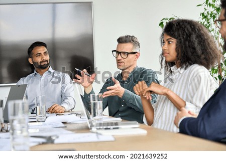 Mature mentor manager speaking at executive team meeting in boardroom. Male leader training executive team at board briefing. Multicultural professional business people discussing strategy in office Royalty-Free Stock Photo #2021639252