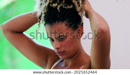 African woman arranging hair. Hispanic latina adjusting hair casual and candid