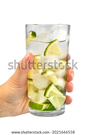 Glass of water with ice and lime in the woman's hand isolated on white background.