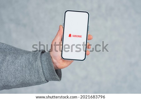 Subscribe to the Internet channel on the smartphone display. Man holds smartphone close-up with icon