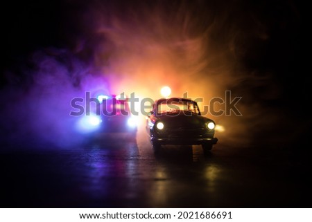 Police car chasing a car at night with fog background. 911 Emergency response police car speeding to scene of crime. Selective focus Royalty-Free Stock Photo #2021686691