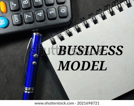 Business concept.Text BUSINESS MODEL writing on notebook with calculator and pen on a black background.