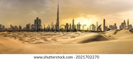Dubai downtown skyline panorama at sunset with desert sand, United Arab Emirates