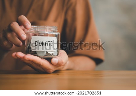 Man holding money jar with DONATE word written text label for giving and donation concept, saving, fundraising charity, Coronavirus economic stimulus rescue package Royalty-Free Stock Photo #2021702651