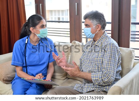 Lady doctor wearing mask on call at home examining Mature man wearing mask Royalty-Free Stock Photo #2021763989