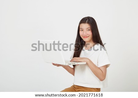 Happy attractive young woman with laptop computer sitting cross legged and looking at empty space on white studio background