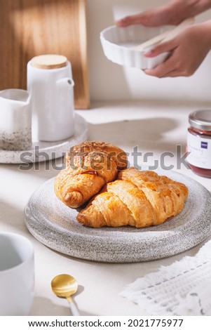 Croissant served on the ceramic plate in bright harsh light. Life style photography. Close up.