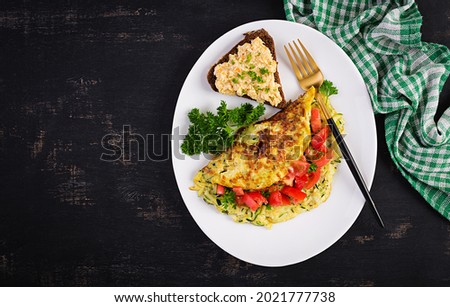 Breakfast. Omelette with zucchini, cheese and tomatoes salad with sandwich on white plate.  Frittata - italian omelet. Top view, flat lay
