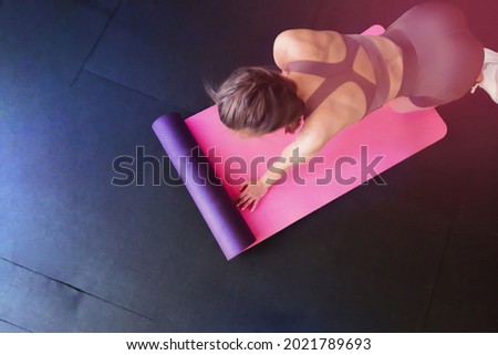 Fitness background for your business. The girl is engaged in pilates on a pink yoga mat. Class Stretching in the gym on a black rubber covering. Exercise stretching cobra. Top view advertising banner