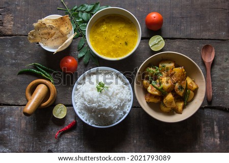 View from top of simple Indian food or meal with potato fry, rice, lentils, papad and condiments. Vegetarian dish. Royalty-Free Stock Photo #2021793089