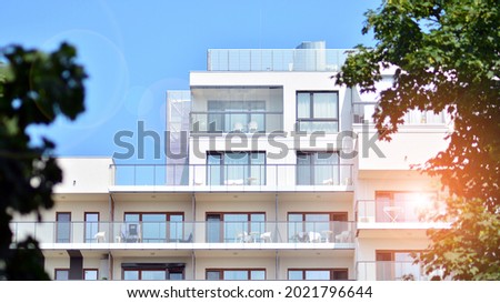 Modern white facade of a residential building with large windows. View of modern designed concrete apartment building. Royalty-Free Stock Photo #2021796644