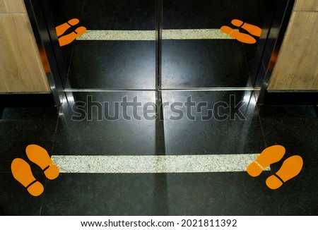 Footprint signage showing social distancing measures on the floor of an elevator.