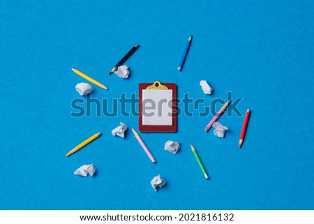 Board and pencils with crumpled papers on blue background 