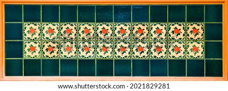 Colourful ceramic tile mosaic with red rose tiles with a  bottle green border. Typical of the designs found on the facades of traditional Chinese shop houses throughout south east Asia.