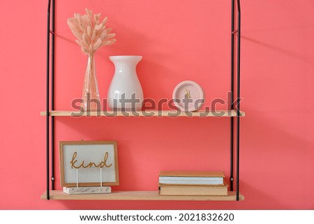 Shelf with alarm clock and decor on color wall