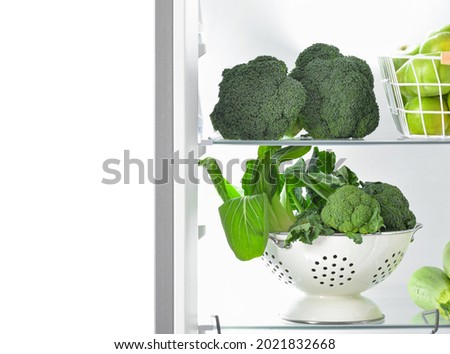 Fresh broccoli and Chinese cabbage in fridge on white background