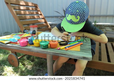 Child boy have a leisure drawing at the backyard, summer holidays